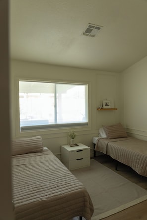 A bedroom with two single beds, a bedside table, a nightstand, a window, and a ceiling vent. - 3-bedroom Desert Escape Near Saguaro Lake & Salt River (Mesa)