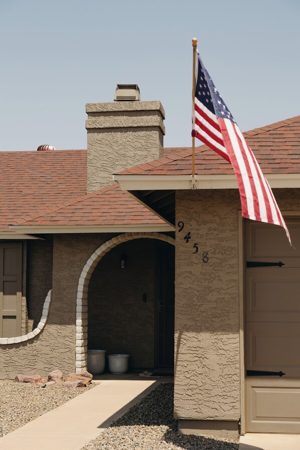 A house with a chimney, an American flag, and a garage door. - 3-bedroom Desert Escape Near Saguaro Lake & Salt River (Mesa)