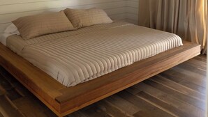 Une chambre à coucher avec un lit, un plancher en bois, un ventilateur de plafond et une fenêtre avec des rideaux.