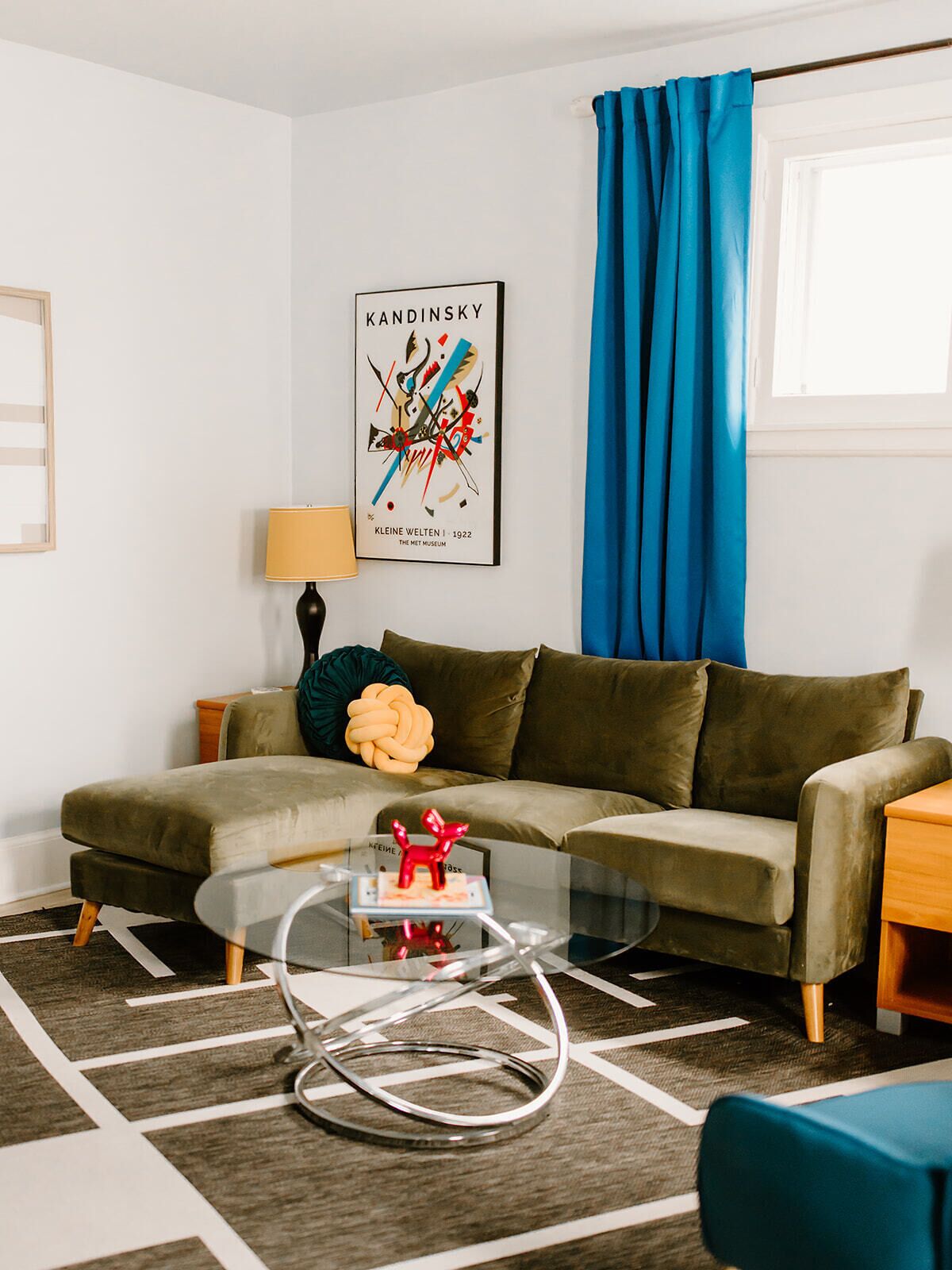 A modern living room with a sofa, a glass coffee table, and a lamp.
