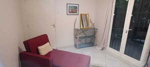 A red sofa with a cushion, a small table with a mirror, and a framed picture on the wall. - 2-bedroom apartment in peaceful Les Trois-Îlets with AC (Les Trois-Îlets)
