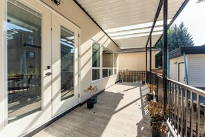 A covered balcony with a wooden floor, potted plants, and a metal railing. - Grand 5BR Luxury Home ! AC and Home Theater (Surrey)