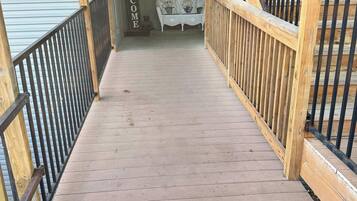 A wooden staircase leading to a porch with a 'WELCOME' sign, a white bench, and a mailbox marked with the number 7.