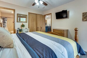 A bedroom with a bed, wooden wardrobe, a television, and a ceiling fan. - Modern Charmer - 2bd 2Bath - 1 mile to Silver Dollar City- Branson West (Reeds Spring)