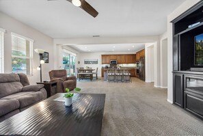 A modern living room with a sofa, a coffee table with a plant, and a dining area with chairs and a table. - Welcome to Casa de Las Mariposas! Single Story, 3 Bed, 3 Bath, Fire Pit & Views! (San Marcos)