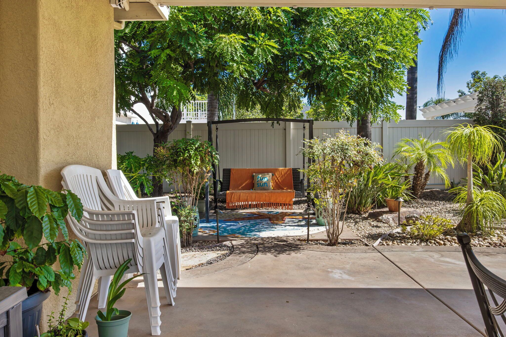 A covered patio area with outdoor seating, a small pool, and various plants.