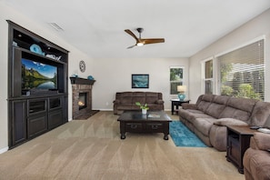 A living room with a fireplace, a television, a sofa, and a ceiling fan. - Welcome to Casa de Las Mariposas! Single Story, 3 Bed, 3 Bath, Fire Pit & Views! (San Marcos)