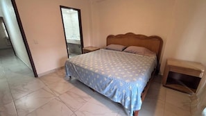 A bedroom with a bed, nightstands, and a wooden headboard. - For rent in one of Manzanillo's most well-equipped and sought-after condominium complexes. (Manzanillo)