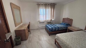A bedroom with a bed, a desk, a chair, a mirror, and a window with curtains. - For rent in one of Manzanillo's most well-equipped and sought-after condominium complexes. (Manzanillo)