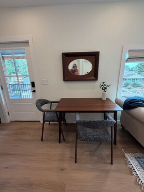 Un área de comedor con una mesa y sillas, una planta en maceta y un espejo en la pared.