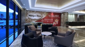 A hotel lobby with seating, a reception desk, and a large wall advertisement. - (Shenzhen)
