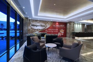 A hotel lobby with seating, a reception desk, and a large wall advertisement. - (Shenzhen)