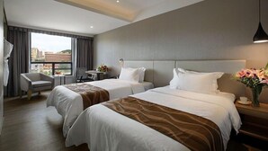 A hotel room with two beds, a desk, a chair, and a view of the city. - (Shenzhen)
