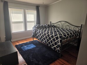 A bedroom with a bed, a black rug, and a window with blinds. - Cozy 3 bedroom house in beautiful Raeford with AC and an office. (Raeford)