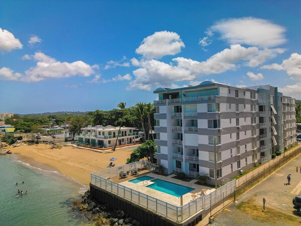 A multi-story hotel with a pool, located near a beach. - Ocean front 2-bedroom condo in lovely Rincon with cool AC (Rincon)