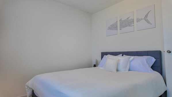 A bedroom with a bed, pillows, and wall art. - Ocean front 2-bedroom condo in lovely Rincon with cool AC (Rincon)
