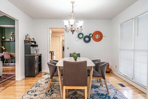 A dining area with a chandelier, a table with chairs, and a decorative wall piece. - The Rocken Lake Hills Retreat (Pinehurst)