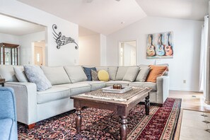 Un salon moderne avec un canapé d’angle, une table basse et un tapis à motifs.