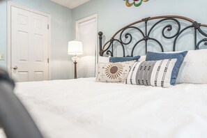 A bedroom with a bed, a nightstand, a lamp, and a door. - The Rocken Lake Hills Retreat (Pinehurst)
