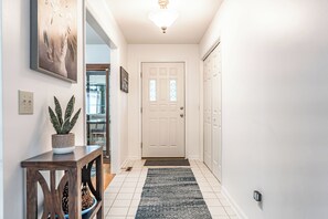 Un couloir avec une porte blanche, une plante en pot et un tapis.