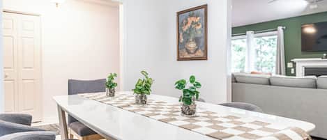 Un espace repas avec une longue table, des chaises et des plantes en pot.