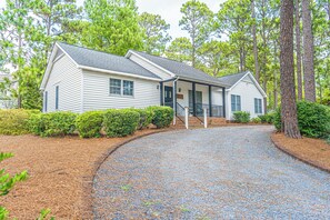 A two-story house with a covered porch and a gravel driveway. - The Rocken Lake Hills Retreat (Pinehurst)
