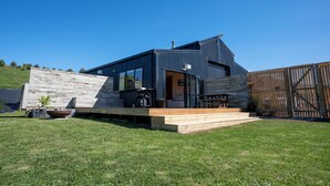 Et moderne hus med træterrasse, patio og en lukket baghave.