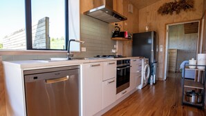 A modern kitchen with wooden cabinetry, stainless steel appliances, and a large window.