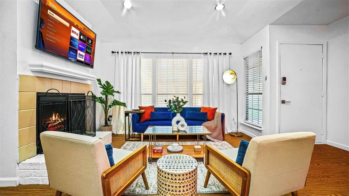 Un salon avec une cheminée, un canapé bleu, une table basse et un téléviseur à écran plat fixé au mur.