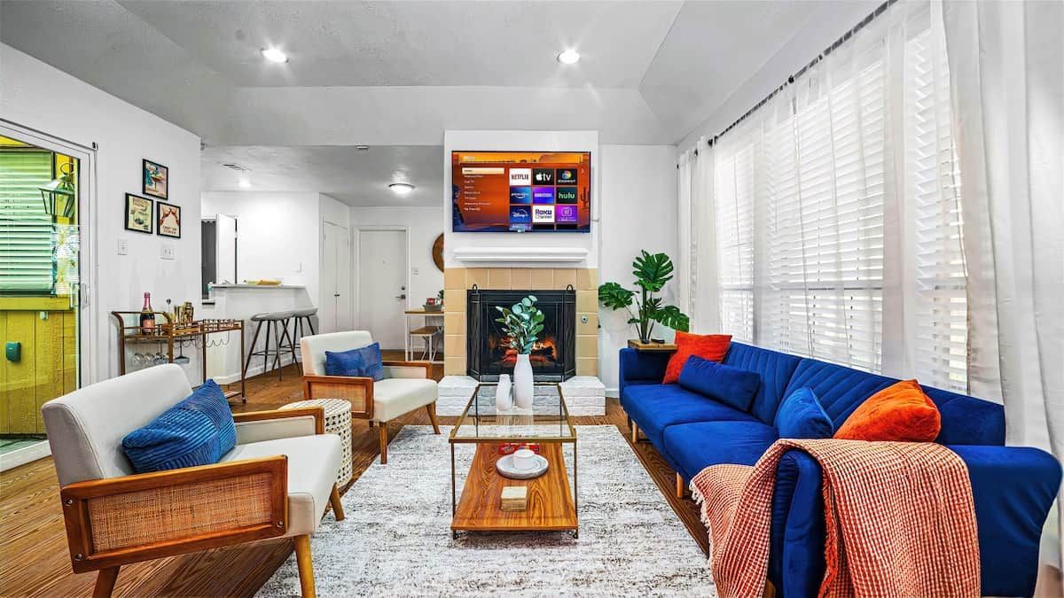 Un salon moderne avec une cheminée, un téléviseur fixé au mur et un coin repas à l’arrière-plan.