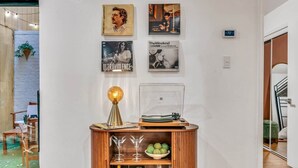 Una habitació amb un armari de fusta que mostra discos i gots, una paret amb quadres i un termòstat que indica 21 graus.