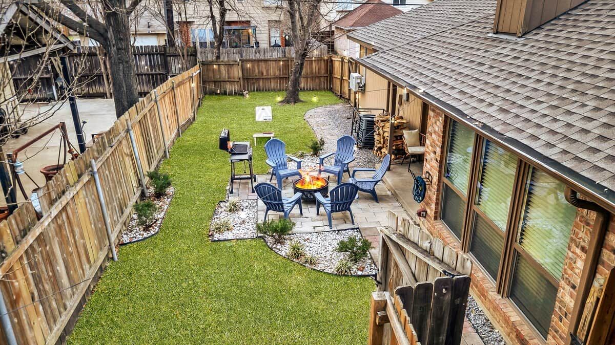 A backyard with a fire pit, outdoor seating, and a wooden fence.