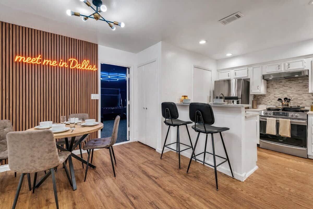 Una cocina moderna con armarios blancos, un refrigerador de acero inoxidable y un horno empotrado.