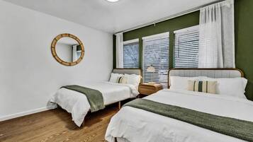 Un dormitorio con dos camas, un espejo redondo y una ventana con persianas.