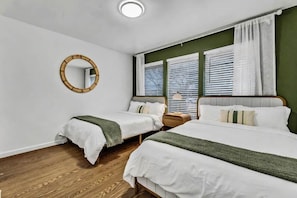 A bedroom with two beds, a round mirror, and a window with blinds. - Retro Dallas Gem: Game Room + Fire Pit (Dallas)