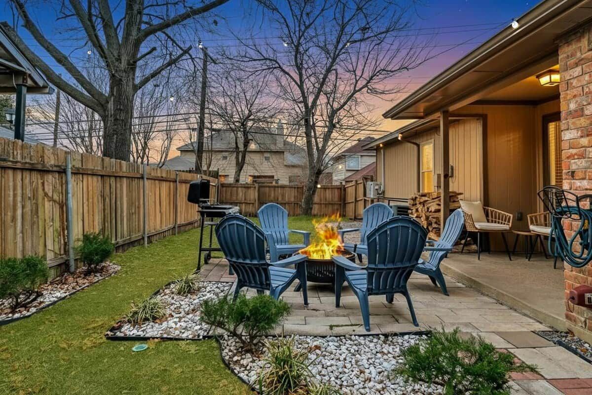 Un patio trasero con un hogar a leña, mobiliario exterior y una valla de madera.