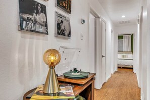 Ein Flur mit Holzboden, einem Plattenspieler auf einem Holztisch und gerahmten Postern an der Wand.