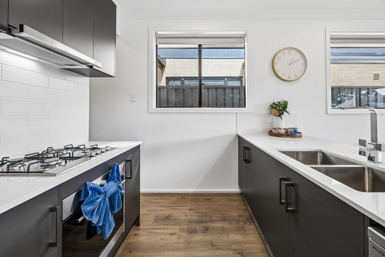 A modern kitchen with a gas stove, stainless steel sink, and a window with a view of buildings.