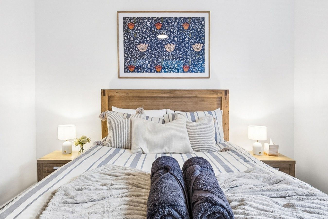 A bed with a striped bedspread, a wooden headboard, and two bedside lamps.
