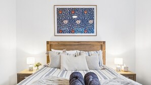 A bed with a striped bedspread, a wooden headboard, and two bedside lamps. - Modern four bedroom home with everything you could possibly need in a prime coast to city location! (South Plympton)