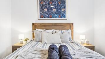 A bed with a striped bedspread, a wooden headboard, and two bedside lamps.