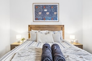 A bed with a striped bedspread, a wooden headboard, and two bedside lamps. - Modern four bedroom home with everything you could possibly need in a prime coast to city location! (South Plympton)