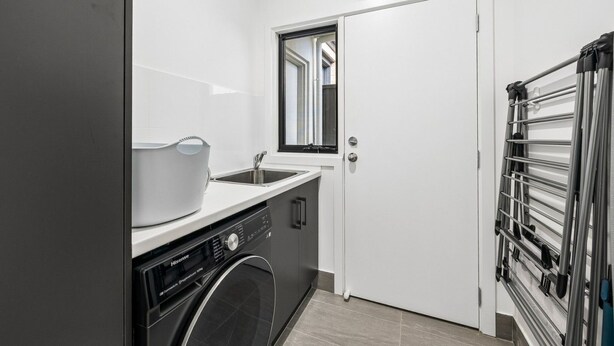 A compact kitchen with a washing machine, a sink, and a drying rack. - Modern four bedroom home with everything you could possibly need in a prime coast to city location! (South Plympton)