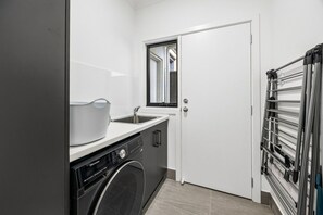 A compact kitchen with a washing machine, a sink, and a drying rack.