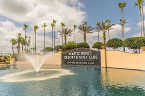 Señal de Mystic Dunes Resort & Golf Club con una fuente al frente.