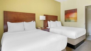 A hotel room with two beds, a nightstand, a lamp, and a painting on the wall.