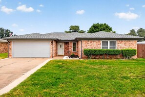 A single-story brick house with a garage, a front lawn, and a small garden area. - Sunshine Shores-Waterfront Lake Granbury Getaway • Sleeps 10 (Granbury)