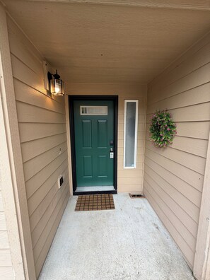 A front door with a green door, a small window, a wall-mounted light fixture, and a potted plant. - 2 Bed 2.5 Bath Townhome with En-Suite bathrooms (Oregon City)