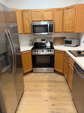 A modern kitchen with stainless steel appliances, wooden cabinets, and a white countertop. - 2 Bed 2.5 Bath Townhome with En-Suite bathrooms (Oregon City)