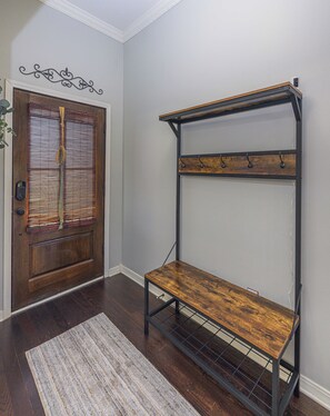 A wooden door with a window, a metal rack with hooks, and a patterned rug on a wooden floor.